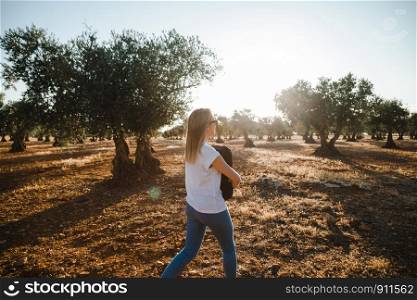 Young woman with a laptop case through the olive field