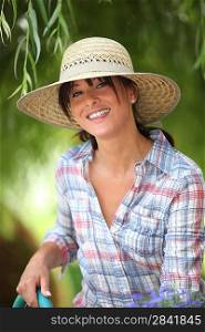 young woman with a straw hat is watering in her kitchen garden