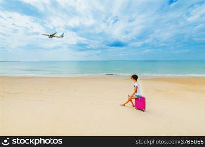 Young woman with a suitcase on the beach