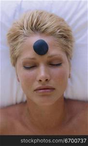 Young woman with a therapeutic stone on her forehead