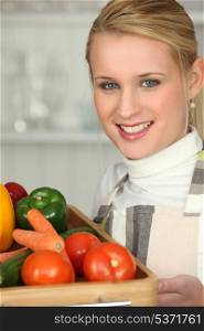 Young woman with a tray of fresh vegetables