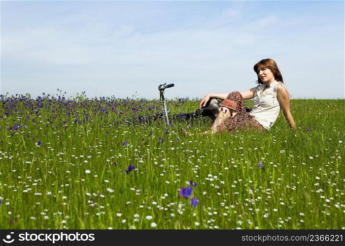 Young woman with a vintage bicycle on a green meadow