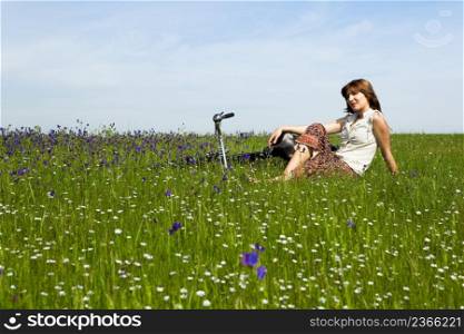 Young woman with a vintage bicycle on a green meadow
