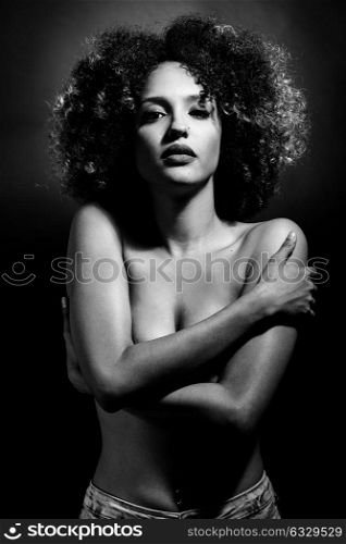 Young woman with afro hairstyle on black background. Studio shot.