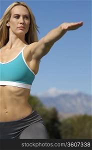 Young woman with arm extended, exercising outdoors
