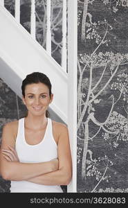 Young woman with arms crossed, leaning against staircase, portrait