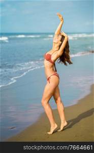 Young woman with athletic body on a tropical beach wearing red bikini. Portrait of a woman with beautiful body on a tropical beach