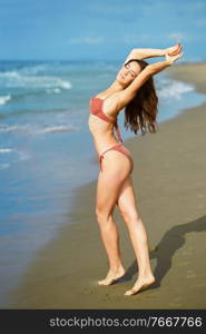 Young woman with athletic body on a tropical beach wearing red bikini. Portrait of a woman with beautiful body on a tropical beach