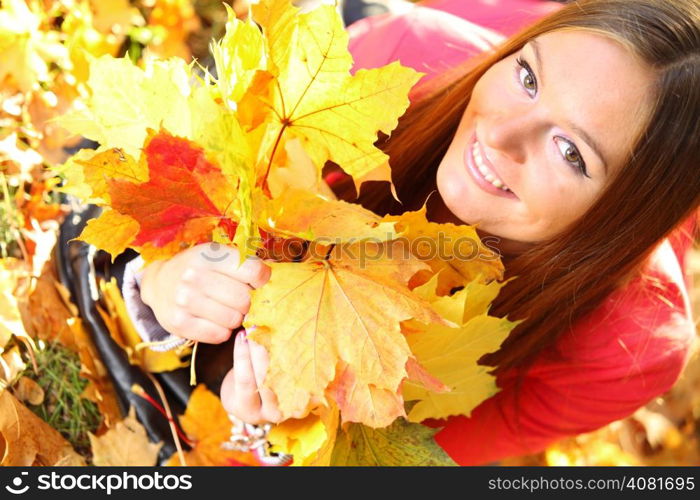 Young woman with autumn leaves in hand and fall yellow maple garden background