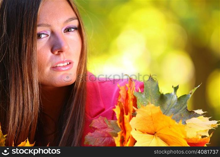 Young woman with autumn leaves in hand and fall yellow maple garden background