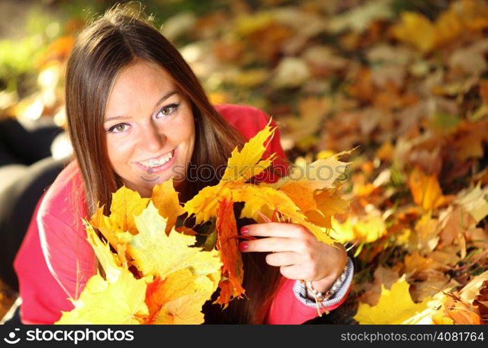 Young woman with autumn leaves in hand and fall yellow maple garden background