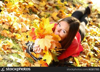 Young woman with autumn leaves in hand and fall yellow maple garden background