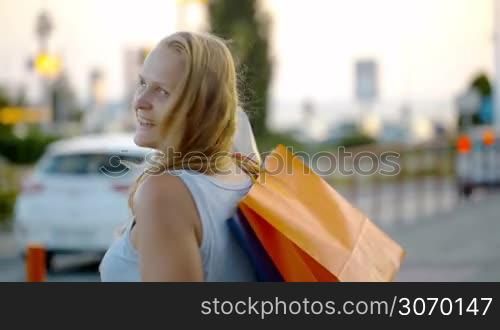 Young woman with bags on the shoulder being happy after good shopping