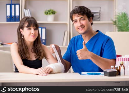 Young woman with bandaged arm visiting male doctor traumotologist . Young woman with bandaged arm visiting male doctor traumotologis