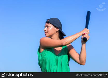 Young woman with baseball bat and cap in blue sky