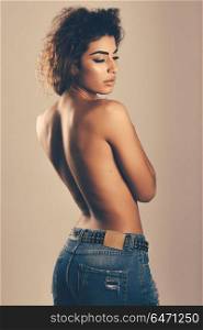 Young woman with beautiful back wearing blue jeans. Girl with beautiful back wearing blue jeans. Young woman with curly hairstyle. Eyes closed.