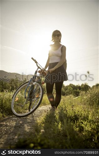 Young woman with bike is enjoying the evening sun