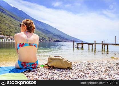 Young woman with bikini is sitting on the beach and enjoying the holidays