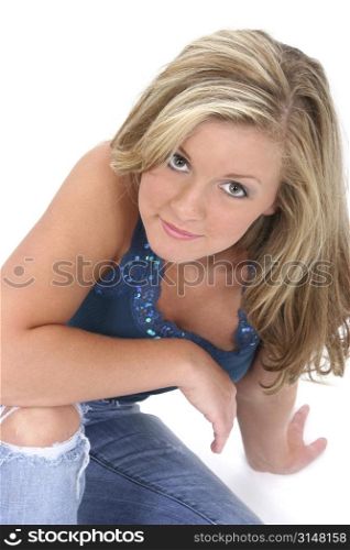 Young woman with blonde hair and stunning hazel eyes. Wearing torn jeans and a decorative tank top looking up. Light make-up and beautiful skin and eyes.