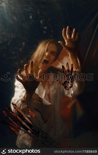 Young woman with bloody hands trying to get away from psychiatrist maniac, mental hospital basement. Victim of doctor butcher in clinic for the mentally ill