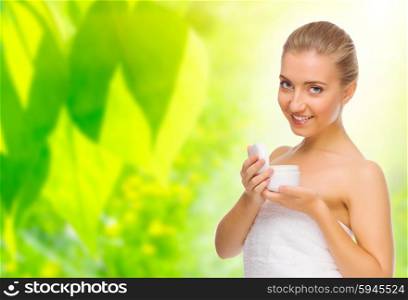 Young woman with body cream on floral background