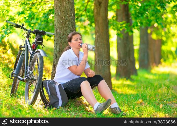 young woman with bottle of water resting near a tree