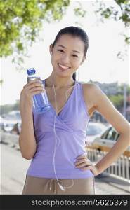 Young Woman with Bottled Water Listening to Music
