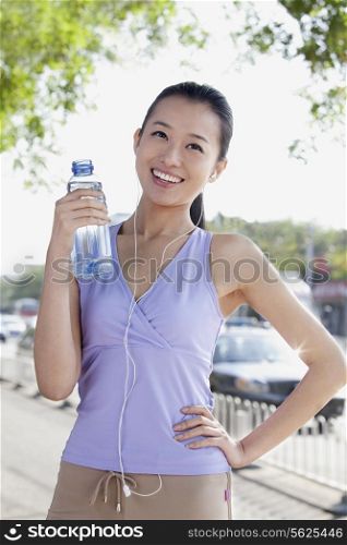 Young Woman with bottled Water while listening Music