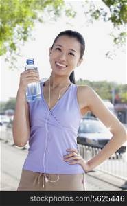 Young Woman with bottled Water while listening Music