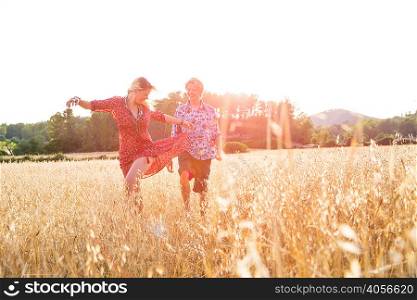 Young woman with boyfriend dancing in wheat field, Majorca, Spain