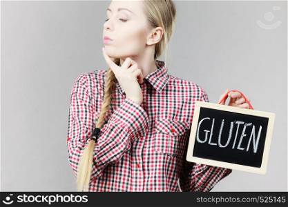 Young woman with braided hair holding small black board with gluten sign. Bakery and bread allergy problem.. Woman holding board with gluten sign