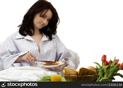 young woman with breakfast in bed. young woman with breakfast in bed applying jam on sandwich