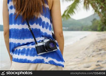 Young woman with camera relaxing and enjoying at the tropical beach, Summer vacation and travel concept