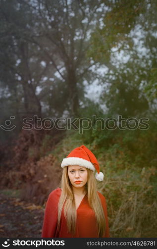 Young woman with Christmas hat and red lips in the forest