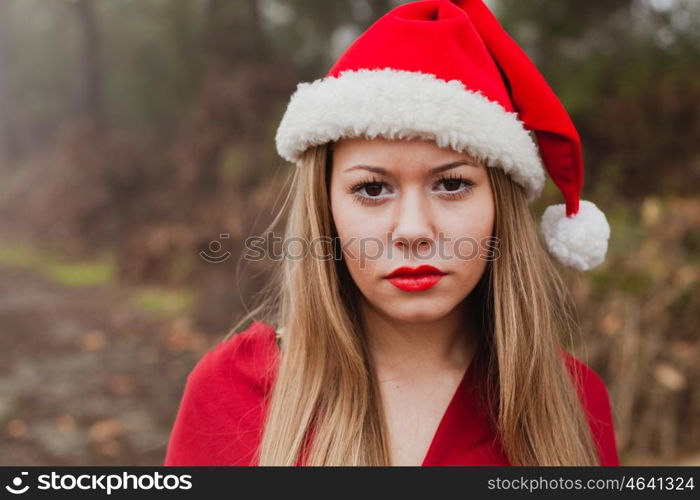 Young woman with Christmas hat and red lips in the forest