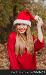 Young woman with Christmas hat and red lips in the forest