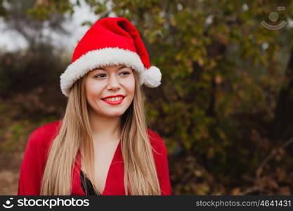 Young woman with Christmas hat and red lips in the forest