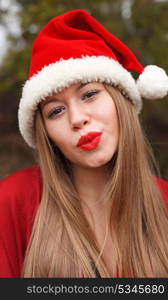 Young woman with Christmas hat and red lips in the forest