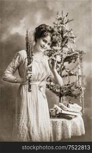 Young woman with christmas tree and gifts. Antique picture with original scratches and film grain