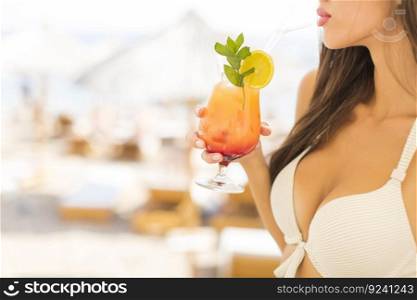 Young woman with coctail on the beach