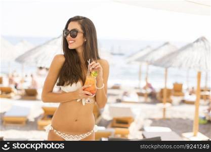 Young woman with coctail on the beach at summer