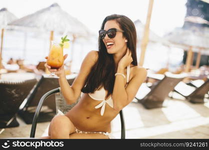 Young woman with coctail on the beach at summer