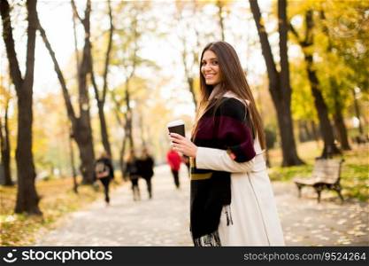 Young woman with coffee in the autumn park. Coffee to go is always a good idea to walk in the autumn park