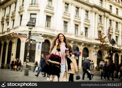Young woman with coffee to go and mobile phone in hand walking down the street