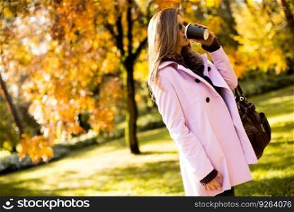 Young woman with coffee to go in the autumn park