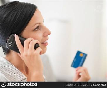 Young woman with credit card and speaking mobile phone