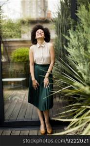 Young woman with curly hair and green skirt posing outdoors