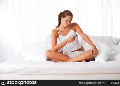 Young woman with earbuds in white holding mp3 player