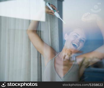 Young woman with electric toothbrush stretching after sleep