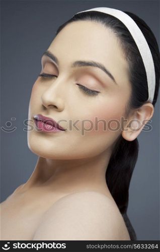 Young woman with eyes closed over colored background